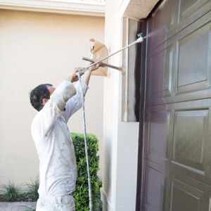 A professional painter painting a garage door